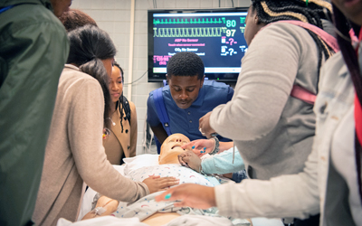 Eric Barksdale (center) and fellow SBIP interns examine Herman, a high-fidelity manikin, during the hands-on portion of their visit to the MASTRI Center.