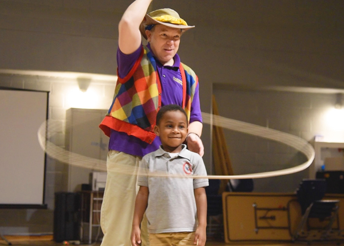 Andrew, a 4-year-old student at James McHenry Elementary/Middle School, helps Greg May, the performing arts manager at Port Discovery, perform a lasso trick.
