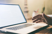 a hand hovering above a laptop keyboard