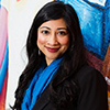 Headshot of woman smiling at camera in front of a colorful background.