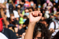 a fist raised with a group of protestors in the background