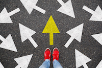 two feet in red shoes on asphalt with painted arrows pointing in different directions