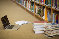 a laptop and books on the floor of a library aisle