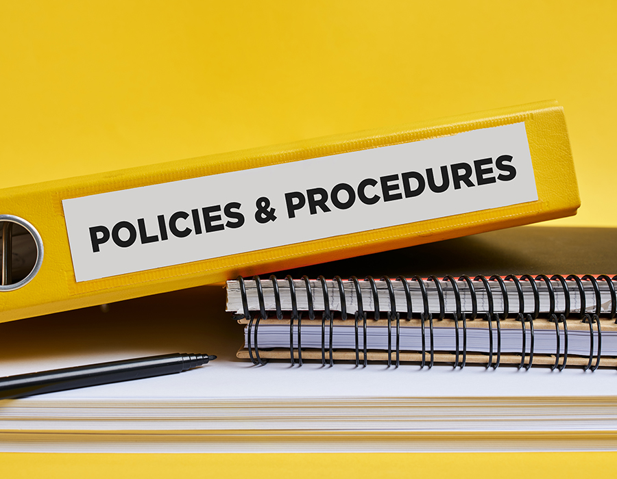 Notebooks and a binder labelled Policies & Procedures