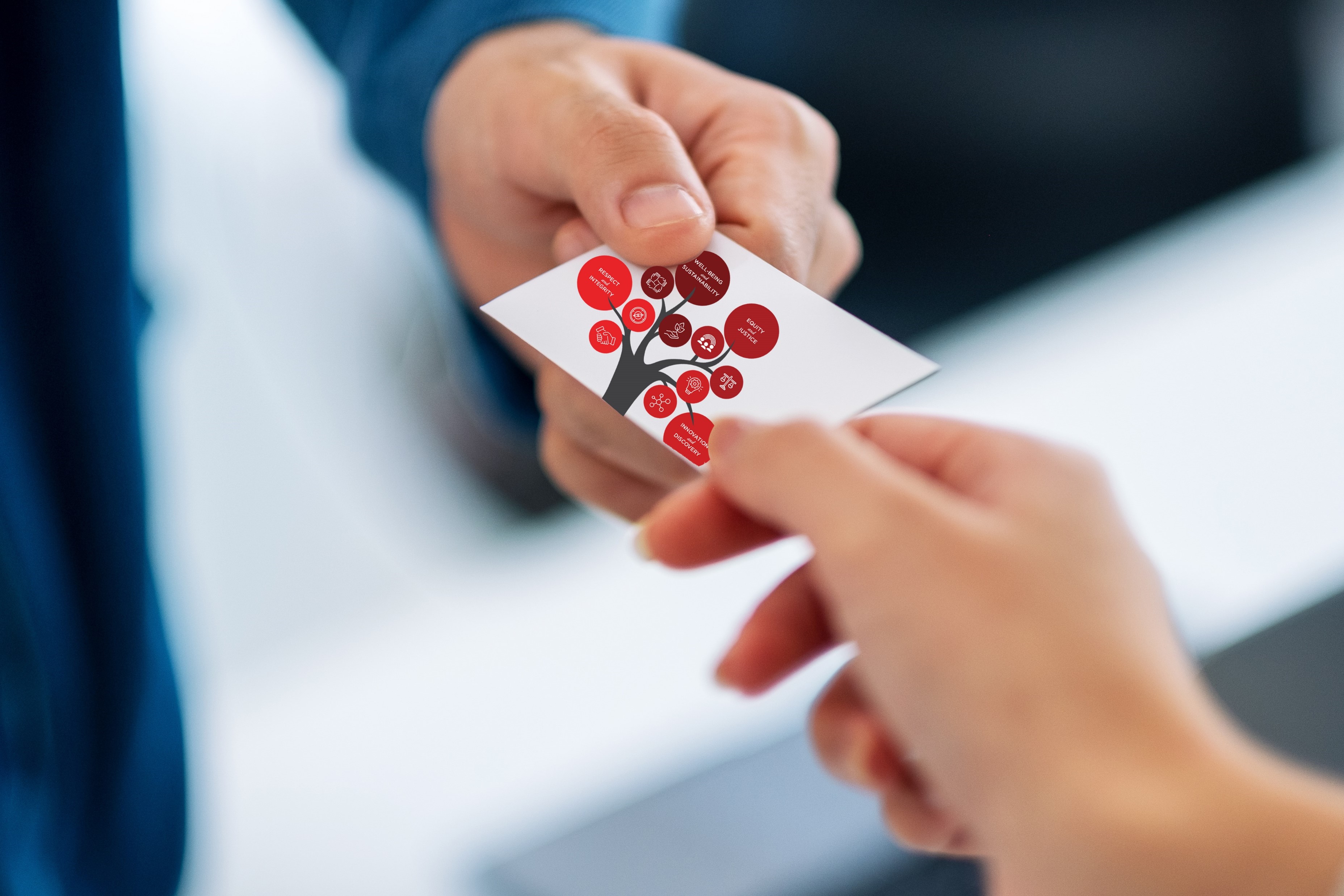 Two hands holding a business card with the image of the Core Values Tree