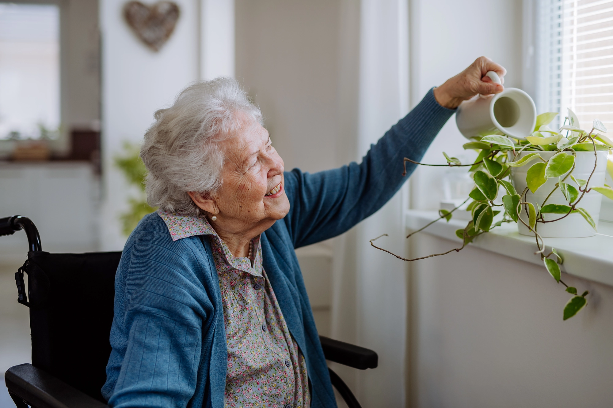 A senior dementia patient watering her flowers in her living area.